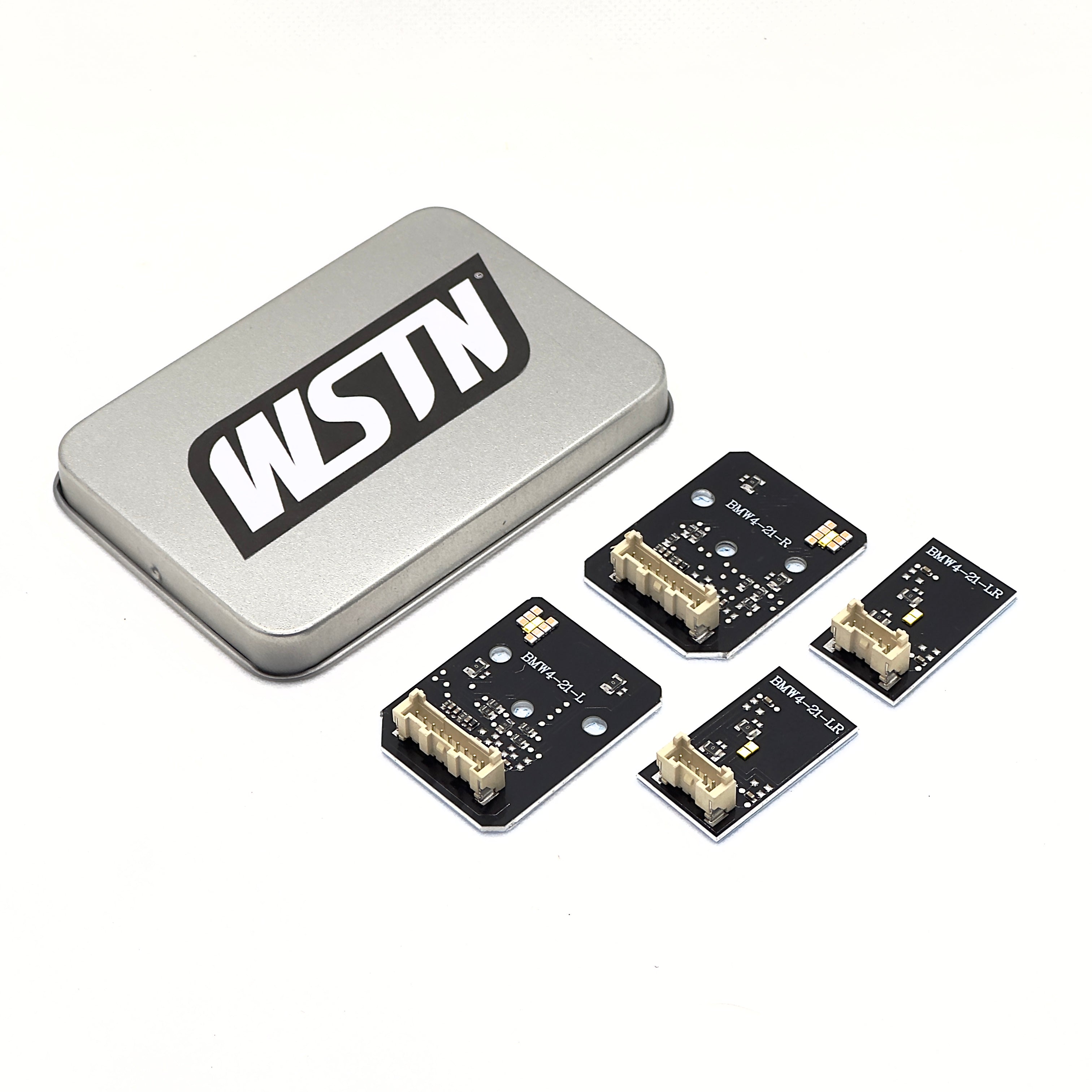 Image showing a set of four WSTN Performance BMW M3/M4/4 Series Yellow CSL DRL Daytime Running Lights LED Module Set, alongside a metal storage tin with the WSTN logo prominently displayed. The modules appear to be suitable for various models, including G80, G81, G82, G83, and G22, in regions like the USA, UK, EU, and Australia