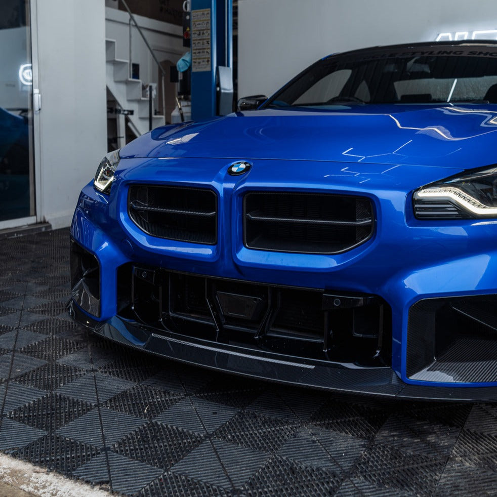 Close-up view of a WSTN Performance carbon fiber front grille designed for a BMW G87 M2, showcasing its intricate weave pattern and glossy finish.