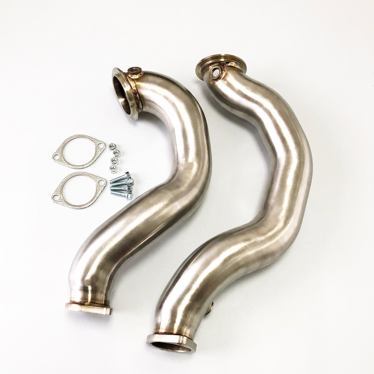 A pair of polished stainless steel S-shaped exhaust manifolds with mounting clamps and screws, displayed on a clean white background.